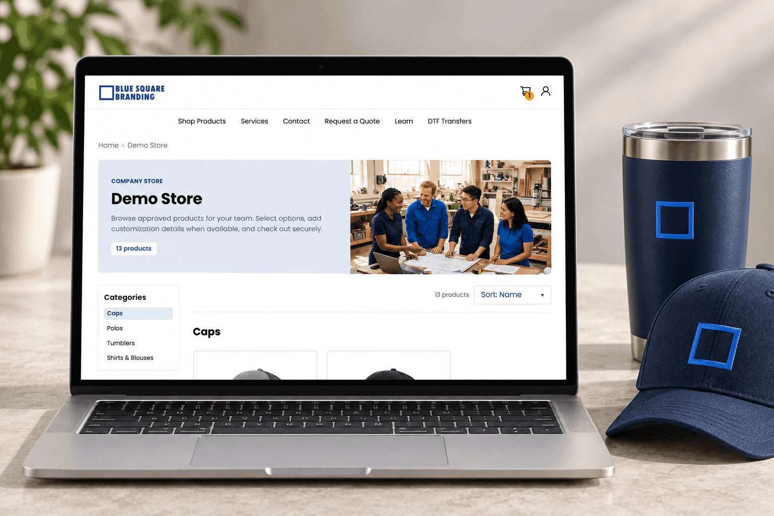 Laptop displaying BSB’s demo company store beside a branded navy tumbler and cap.